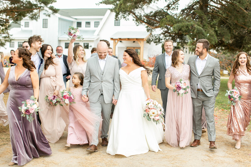 A wedding party walking toward the camera, wearing purples, pinks, grays, and white.