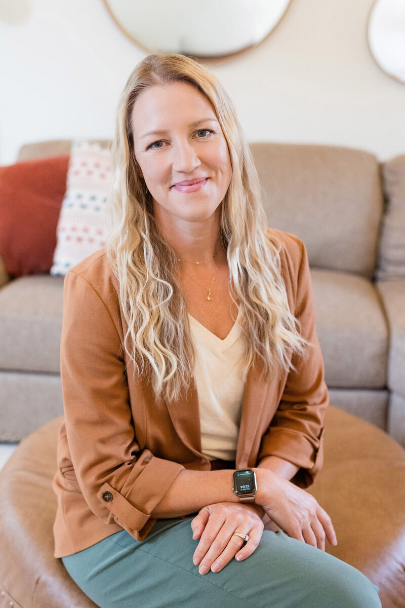 Parent coach Amy Fink sitting on an ottoman in her living room