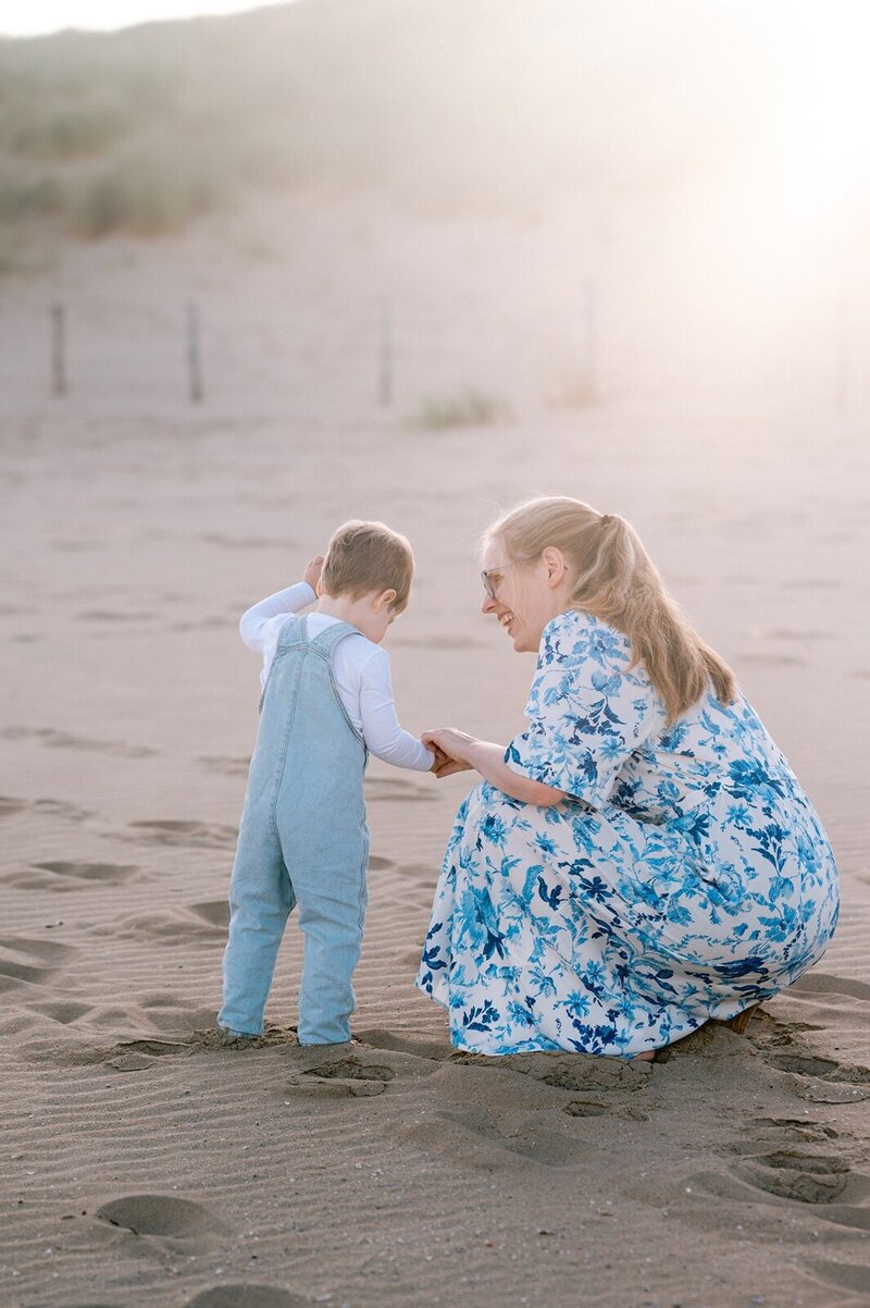 Moeder en zoontje zoeken samen naar schelpjes op het strand