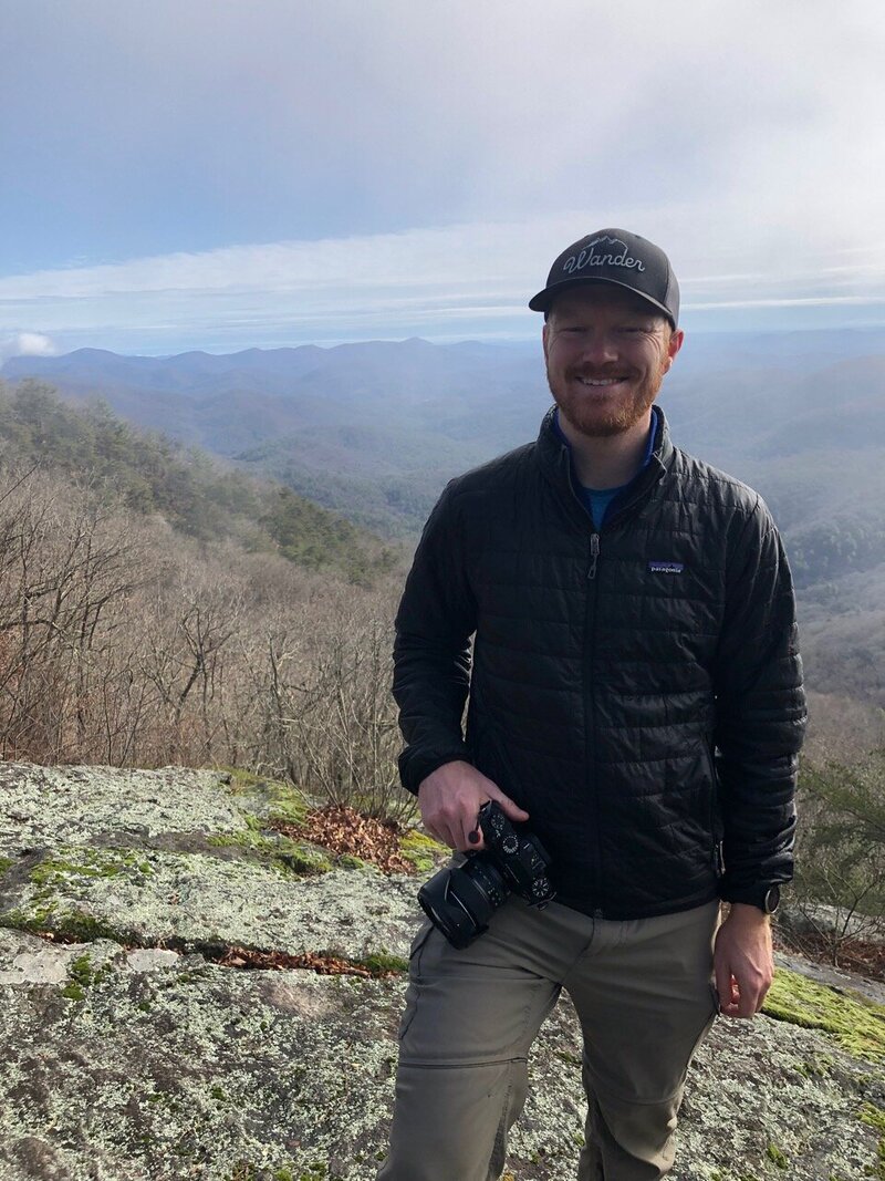 Photographer poses with camera overlooking the mountains