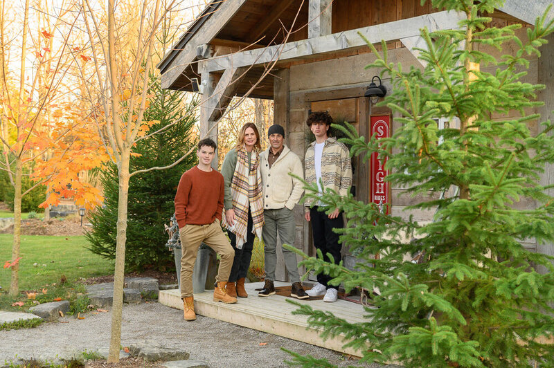 Mom and dad with their teenage sons standing on a cabin porch for their Burlington family photos.