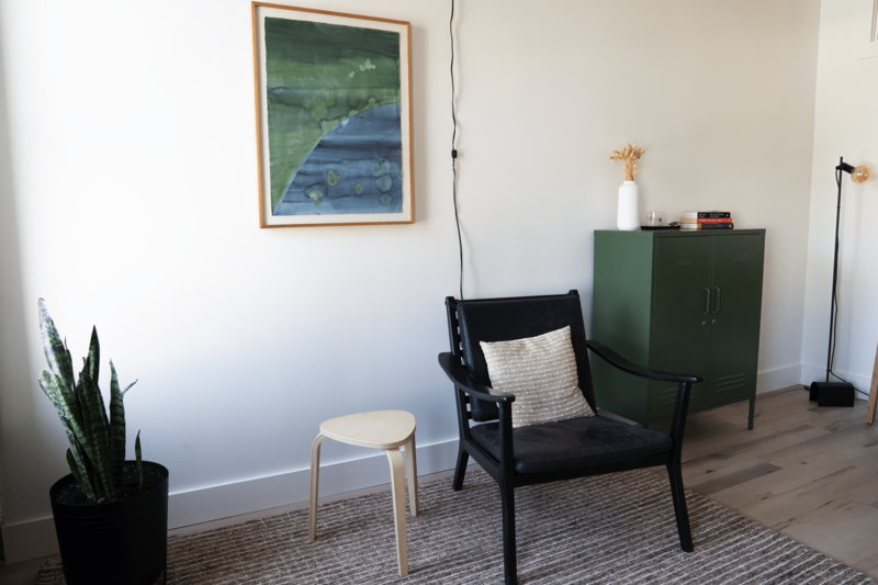 New York therapy office furnished with a large painting, cozy rug, chair and storage space.