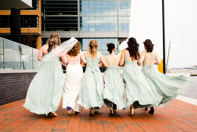 Bridesmaids walk way from camera as gowns flow in the wind, Baltimore Wedding Photographer
