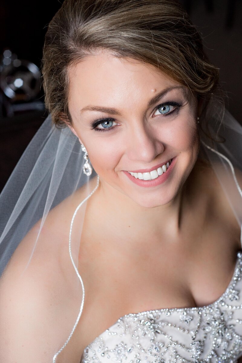 a bride with bright blue eyes looks up at the camera with a smile.