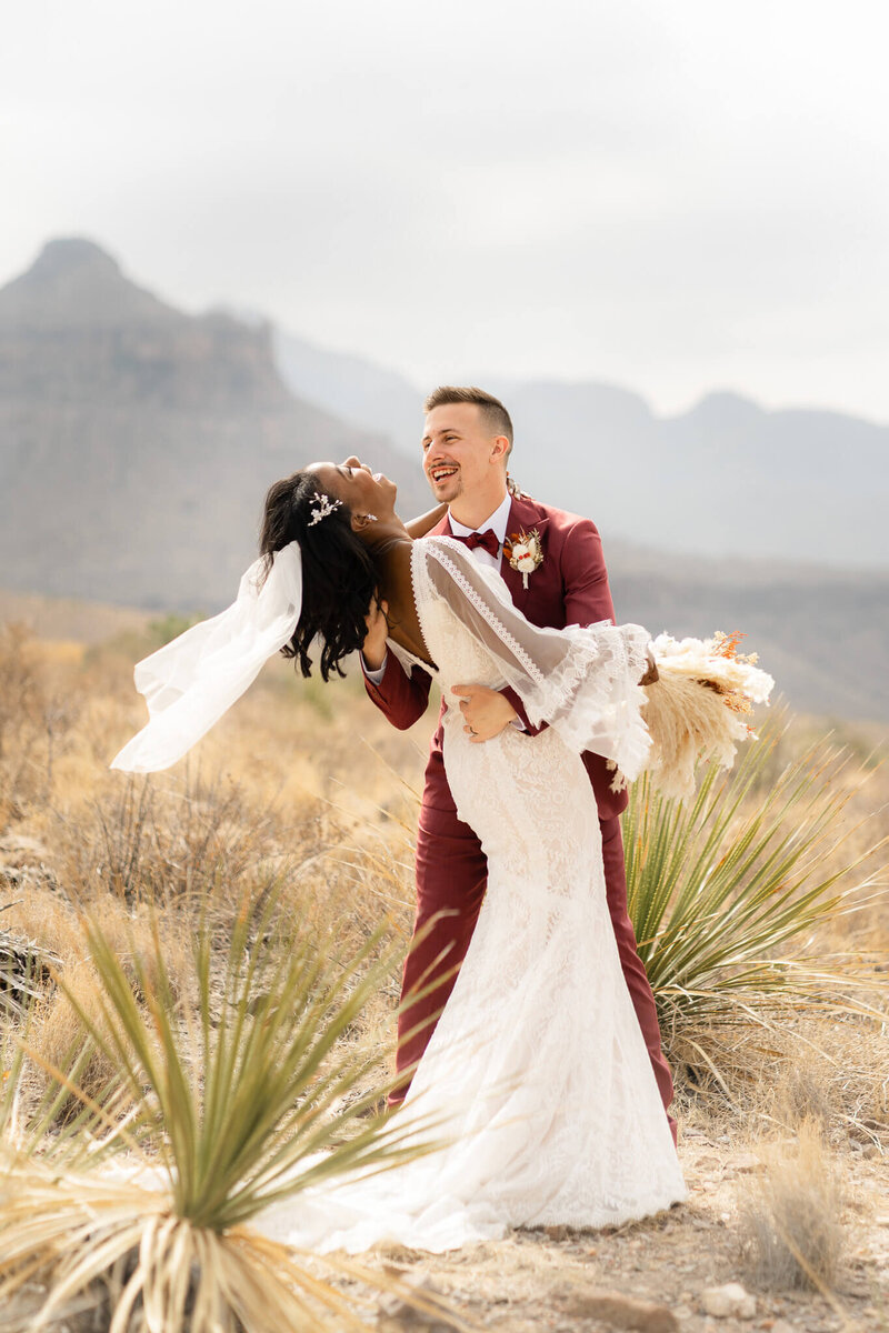 Bride and groom embrace in Rocky Mountain National Park as clouds roll across the mountains behind them on a fall evening