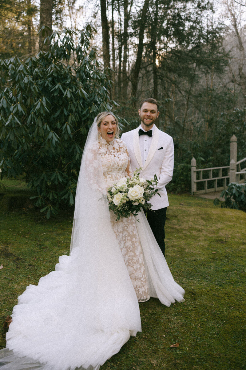 Bride and Groom beaming wiht laughter among the rhododendrons at The Farms at Old Edwards Inn in Highlands, NC, captured by Andrea-Marie Photography