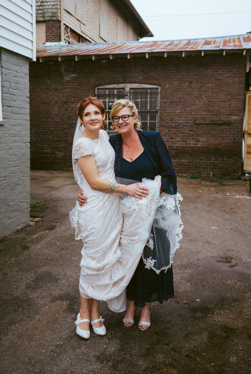 bride in white dress hugging mother