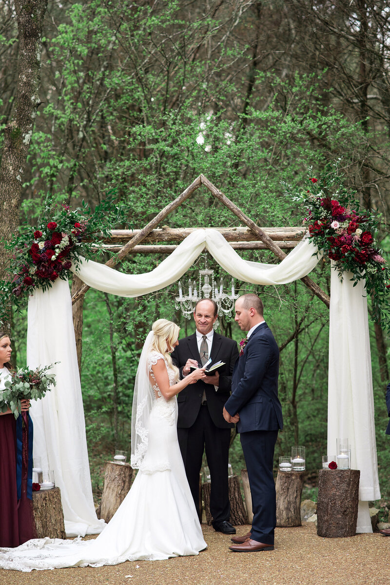 Outdoor ceremony at winter time at Drakewood Farm, bride is reading vows to her husband to be