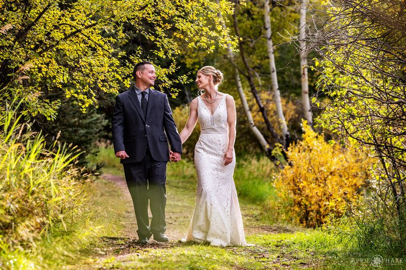 Wedding Couple Walk Through a Pretty Fall Color Forest on their Wedding Day at Beaver Ranch Event Center