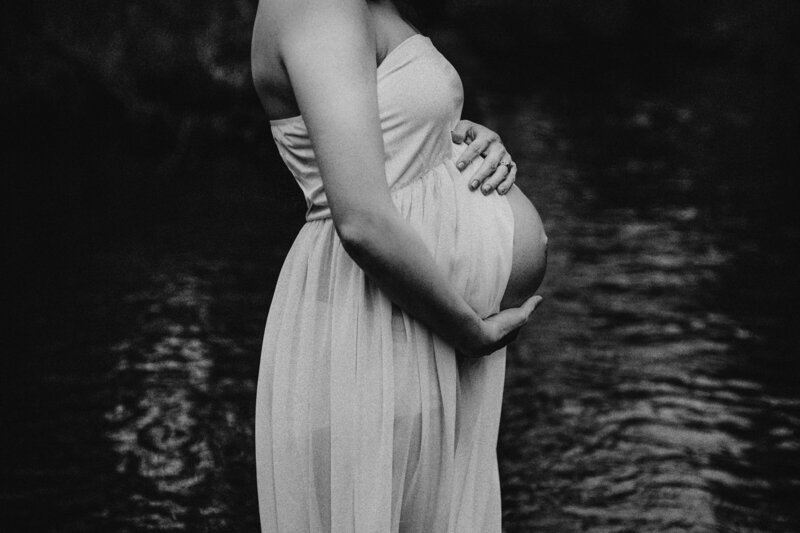 pregnant mother holding her belly by water