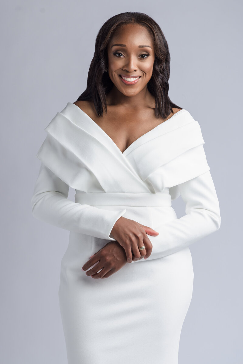 Atlanta & Dallas wedding planner, Paula Ewers, smiles for photo in front of wedding reception table in white dress