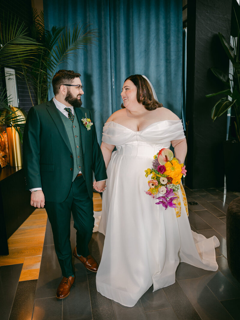 Cambria Hotel wedding portrait of plus size bride and groom with teal curtain and colorful bouquet 