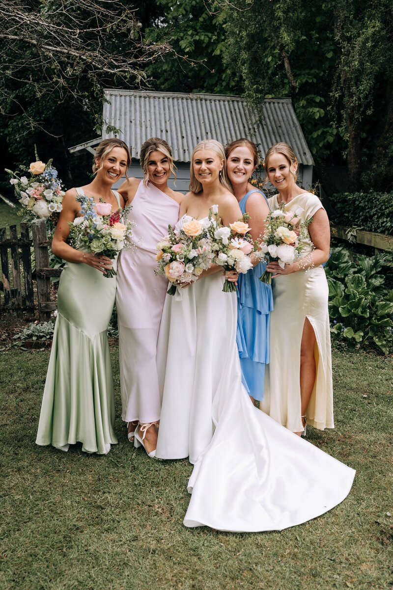 posed photo of bridesmaids in pastel mismatched dresses with pastel florals at waimumu gore