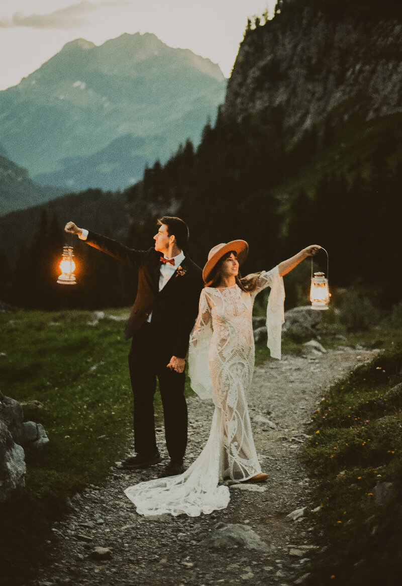 An photo on film of a couple at dusk. They have their elopement at Lake Oeschinen and hold petrol lamps.
