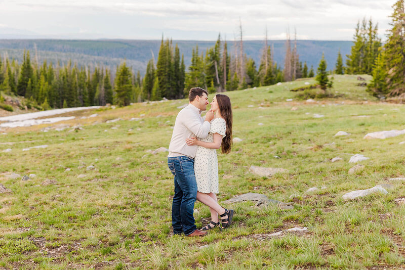 Engaged couple sharing a loving embrace during their sunrise engagement session in the stunning Snowy Range Mountains, surrounded by breathtaking natural scenery.