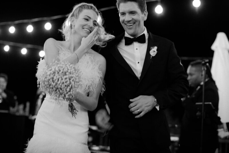 fun black and white image of couple during reception with feather dress and black tux