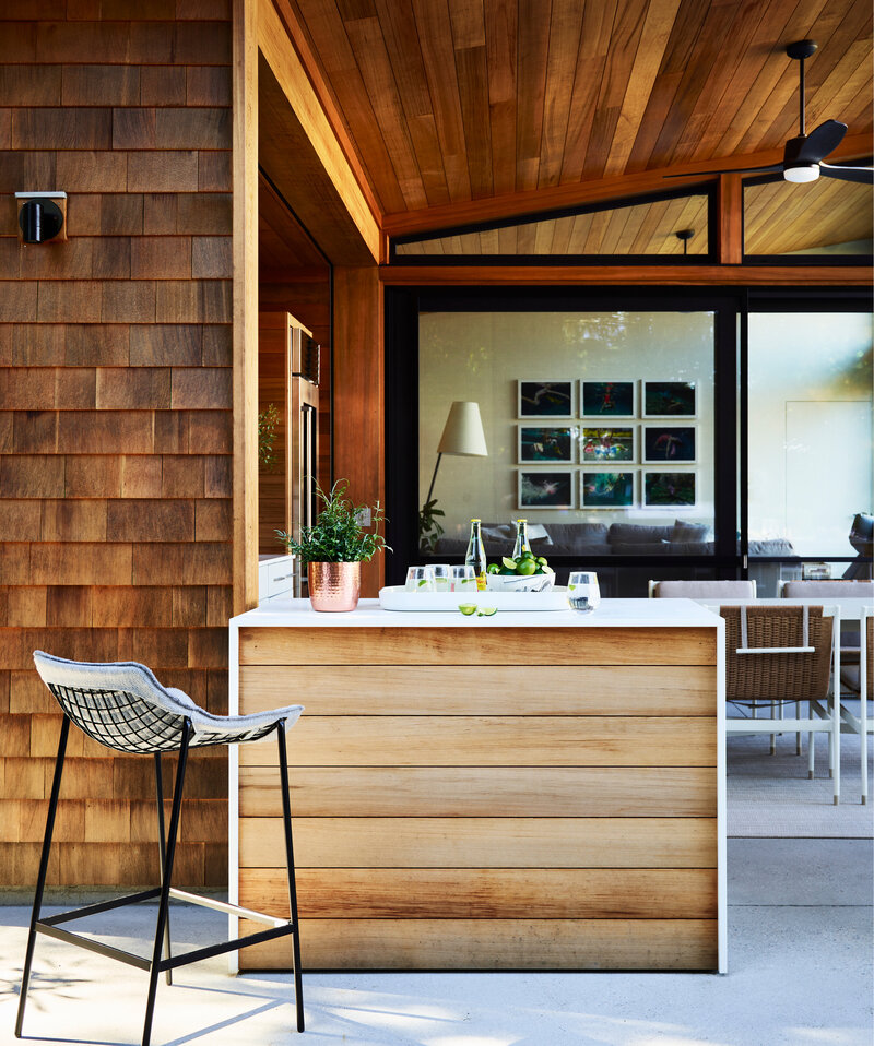 Boston interior designer Sarah Scales crafts a modern Hingham pool house with outdoor kitchen and living areas, blending style and function for perfect outdoor living.