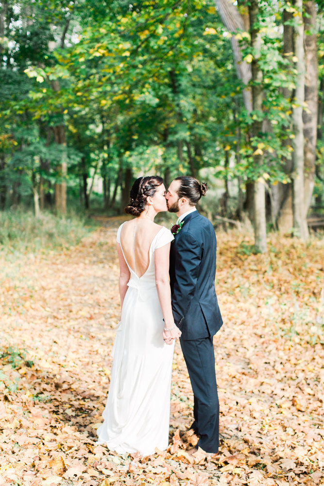 Newly married couple kissing in the park during fall