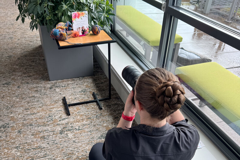 Jen Stitt photographing wedding day details near a hotel window, using soft natural light to highlight intricate textures and design elements.