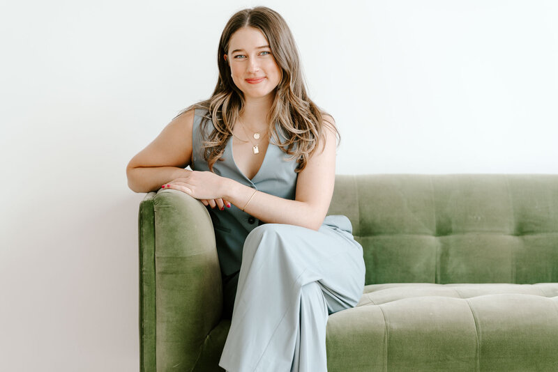 brand headshot of a woman in professional clothing on a green couch
