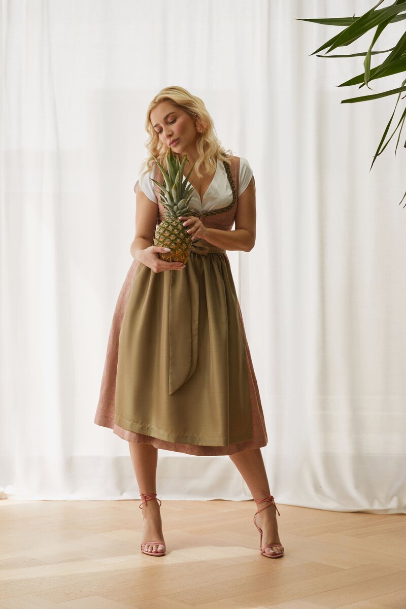 Frau im eleganten Designer-Dirndl in Olivgrün und Rosé von Monaco Spatzl, handgefertigt in München – stilvolle Trachtenmode mit modernem Twist. 
