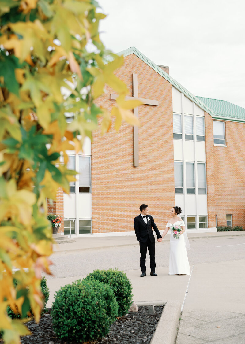 A bride and groom walking by their Church in Grand Rapids