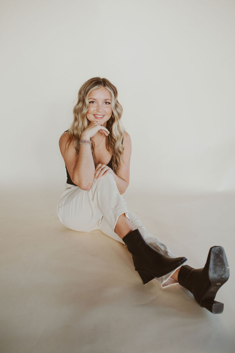 woman smiling while sitting on the floor resting her head on her hand