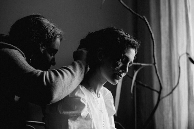 black & white photo of two women preparing each other for filming