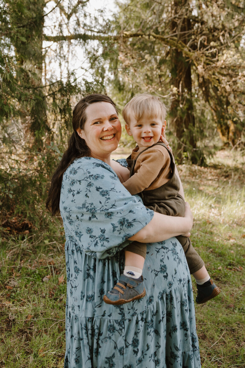 Maternity Photographer holding a toddler and smiling at a park in Oregon