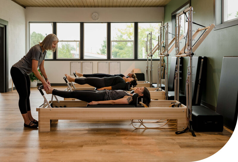 Classical Pilates Teacher Working With Clients on Reformers at Milwaukie Pilates