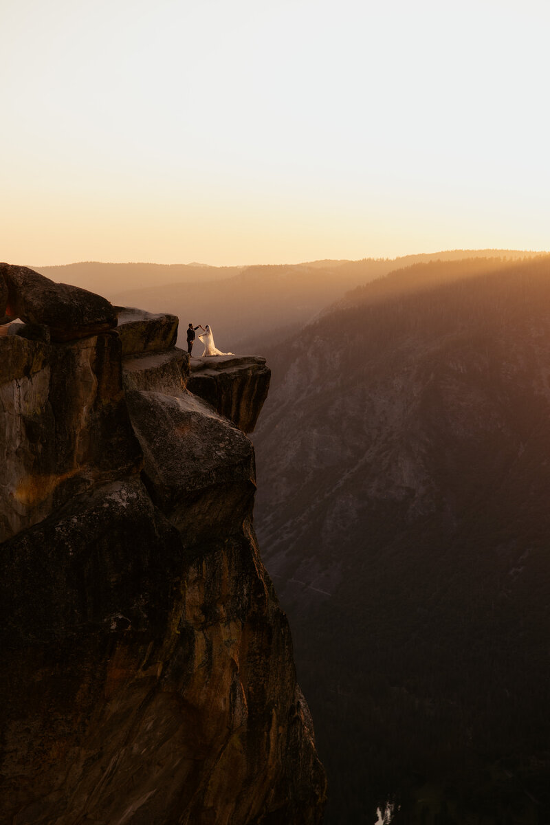 bride and groom standing at taft point in yosemite on their elopement day