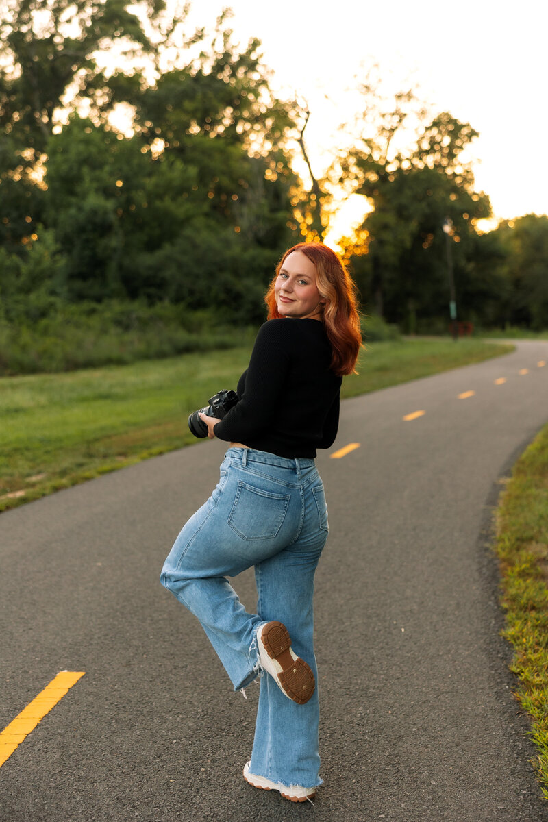 Madison McKenzie Holmes posing for a playful headshot on a road. 