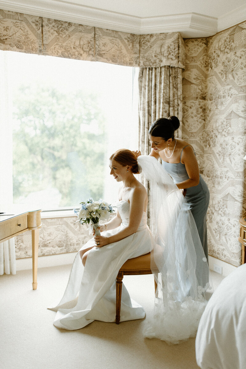 Maid of honor places veil in bride's hair in the Presidential Suite at The Four Seasons Boston, Massachusetts
