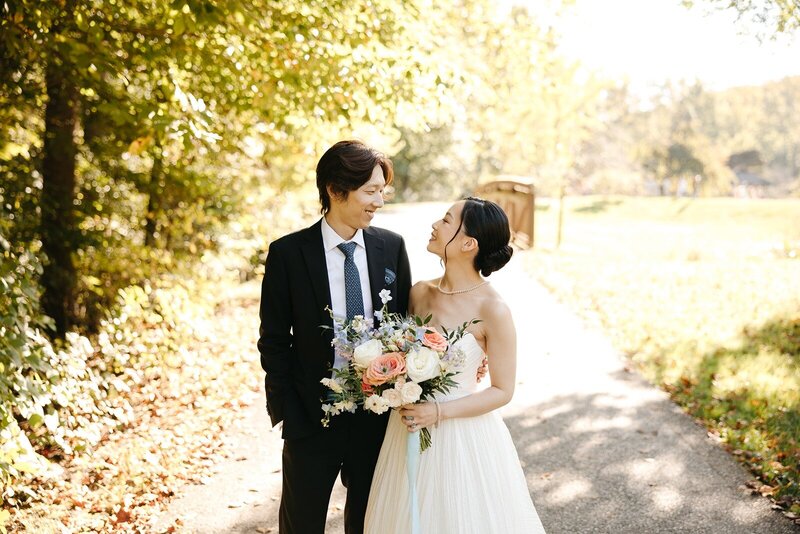 Bride holding bouquet smiling at groom outdoors