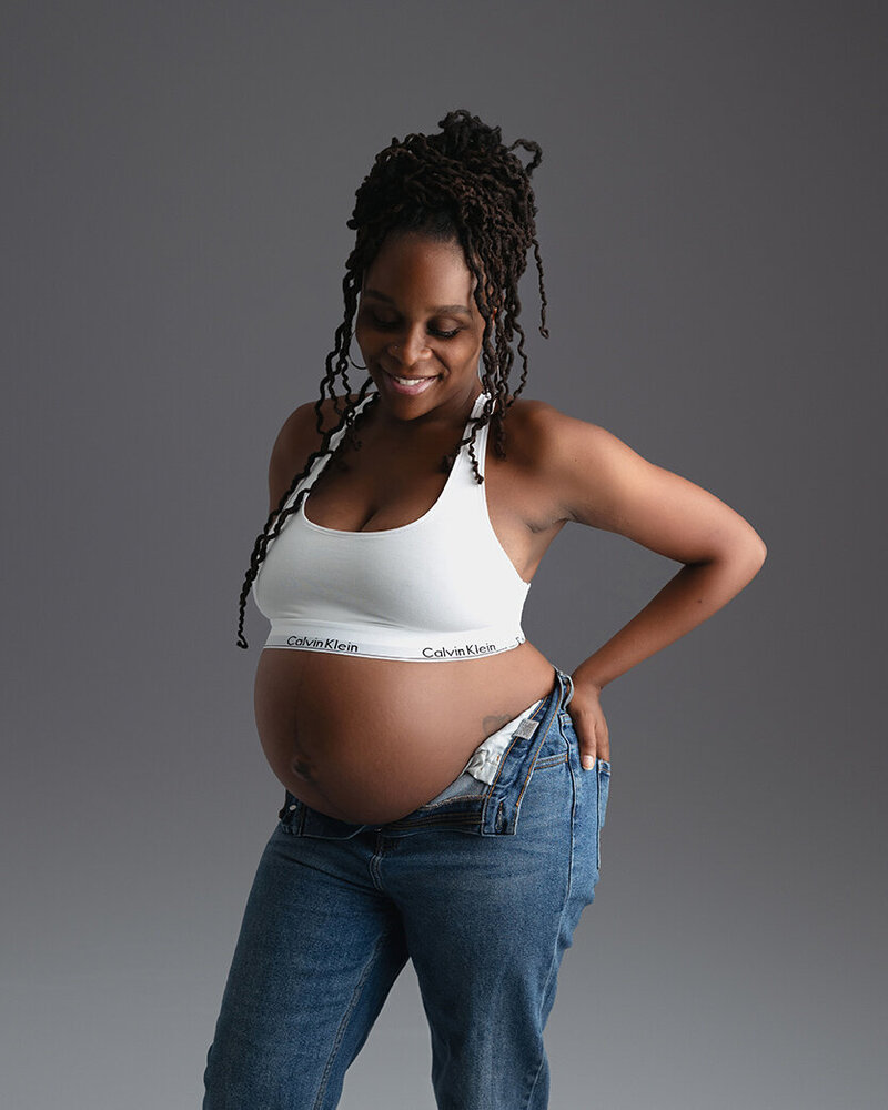 Maternity mom to be has hands on hip for her relaxed Calvin Klein style.