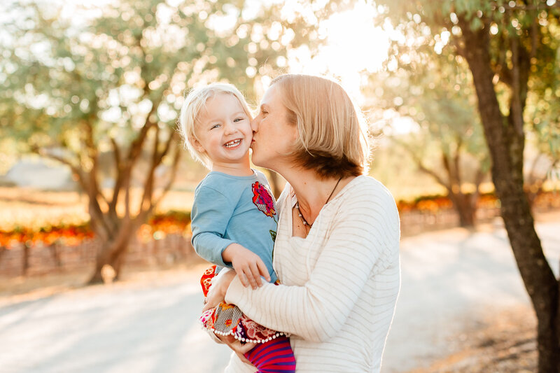 Mom holding and kissing her toddler daughter for a family photography session in San Luis Obispo