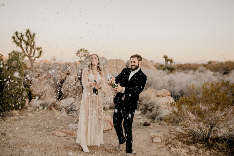 bride and groom popping champagne in the desert