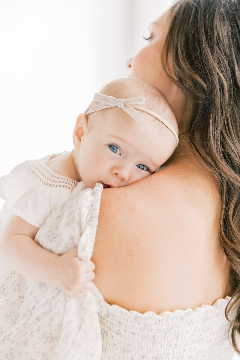 An image taken by a Charlotte Family Photographer of an infant girl resting on mom's shoulder