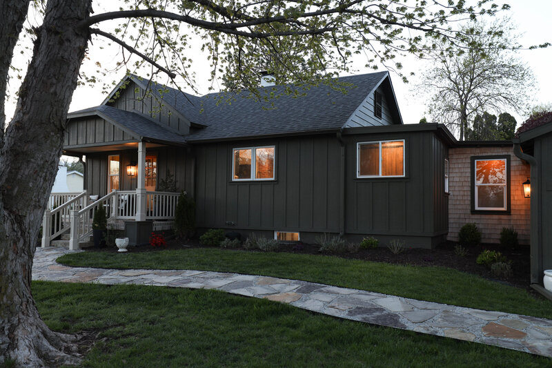 The exterior project by Nadine Stay. Board and batten siding install. Muddled Basil by Sherwin Williams exterior paint color. Flagstone path, brick front porch floor, and a custom built railing. Cabin exterior.