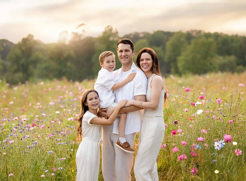 Family standing in wildflower field and smiling at camera. Photographed by Atlanta Family Photographer, Jenni Nikki Photography.