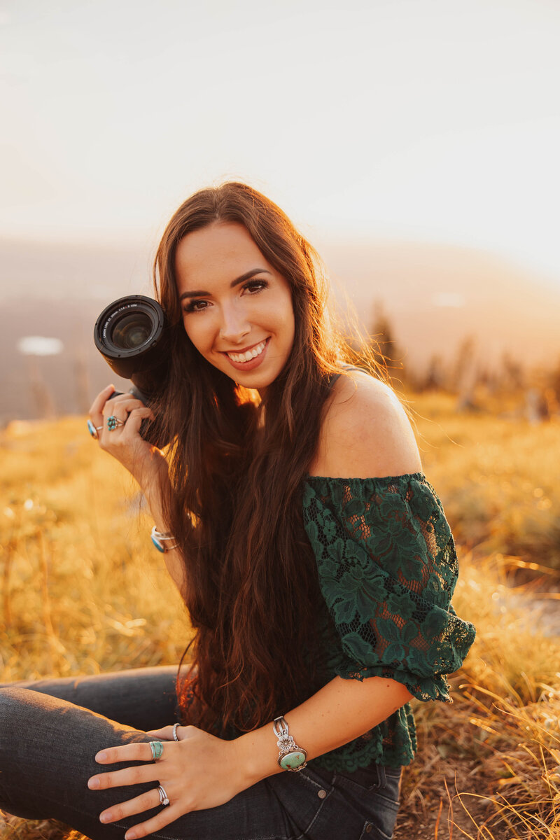 Aurelia smiling while holding her camera, captured during golden hour.