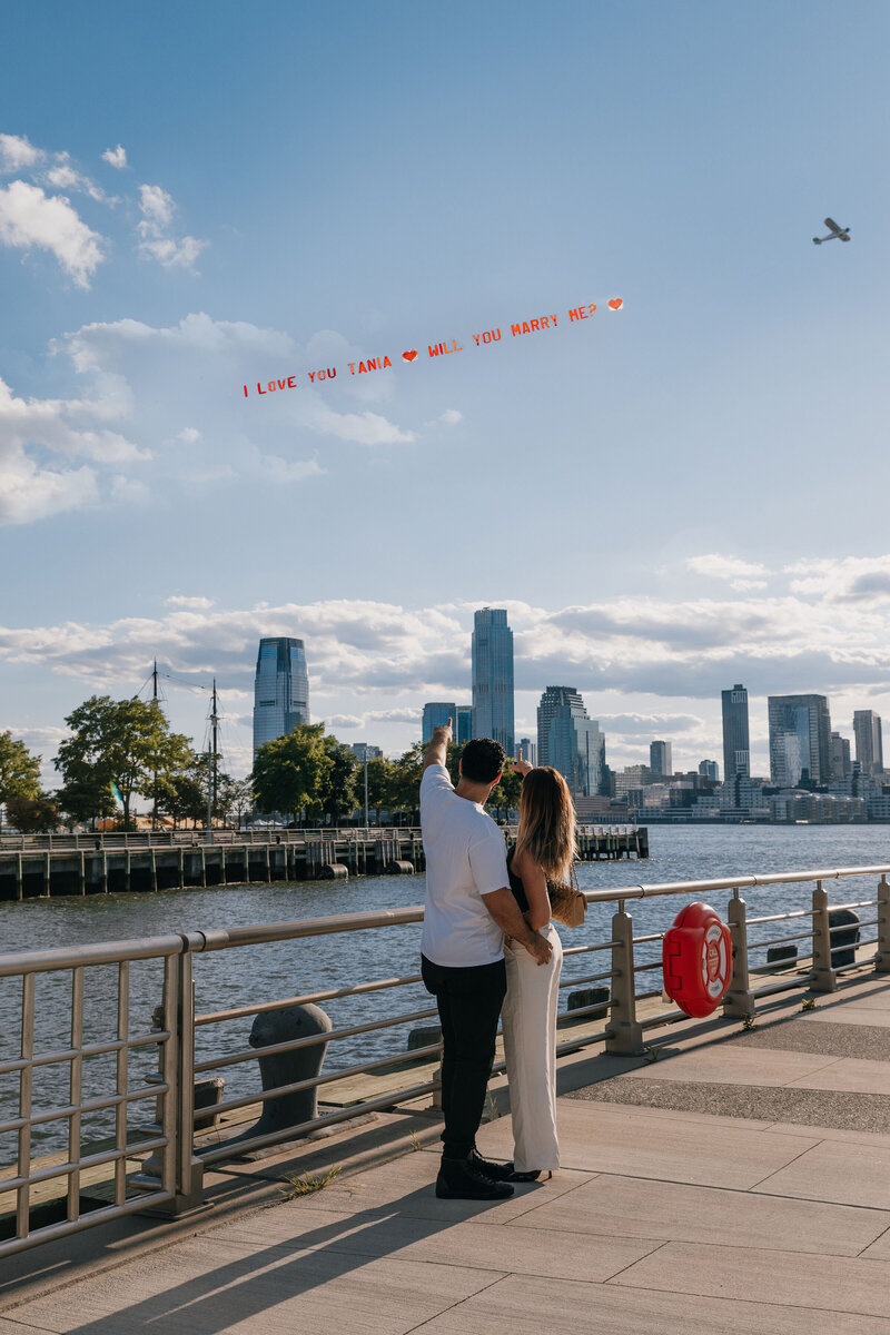 Romantic surprise proposal at the top of the Empire State Building with the NYC skyline in the background.