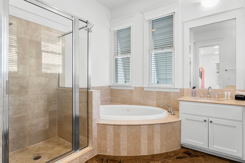 Spa-style bathroom with glass walk-in shower and jetted soaking tub in PCB vacation home.