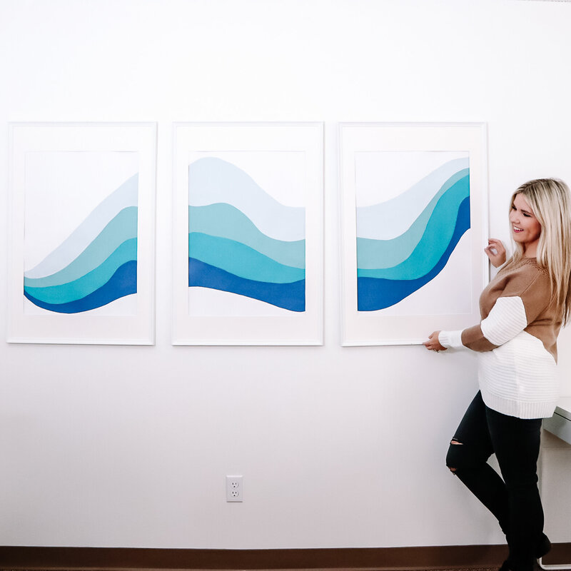 woman hanging painting on a wall