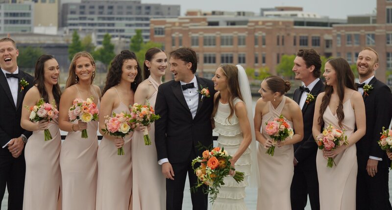 Husband and wife smile with bridal party on the rooftop of the Sagamore Pendry Baltimore