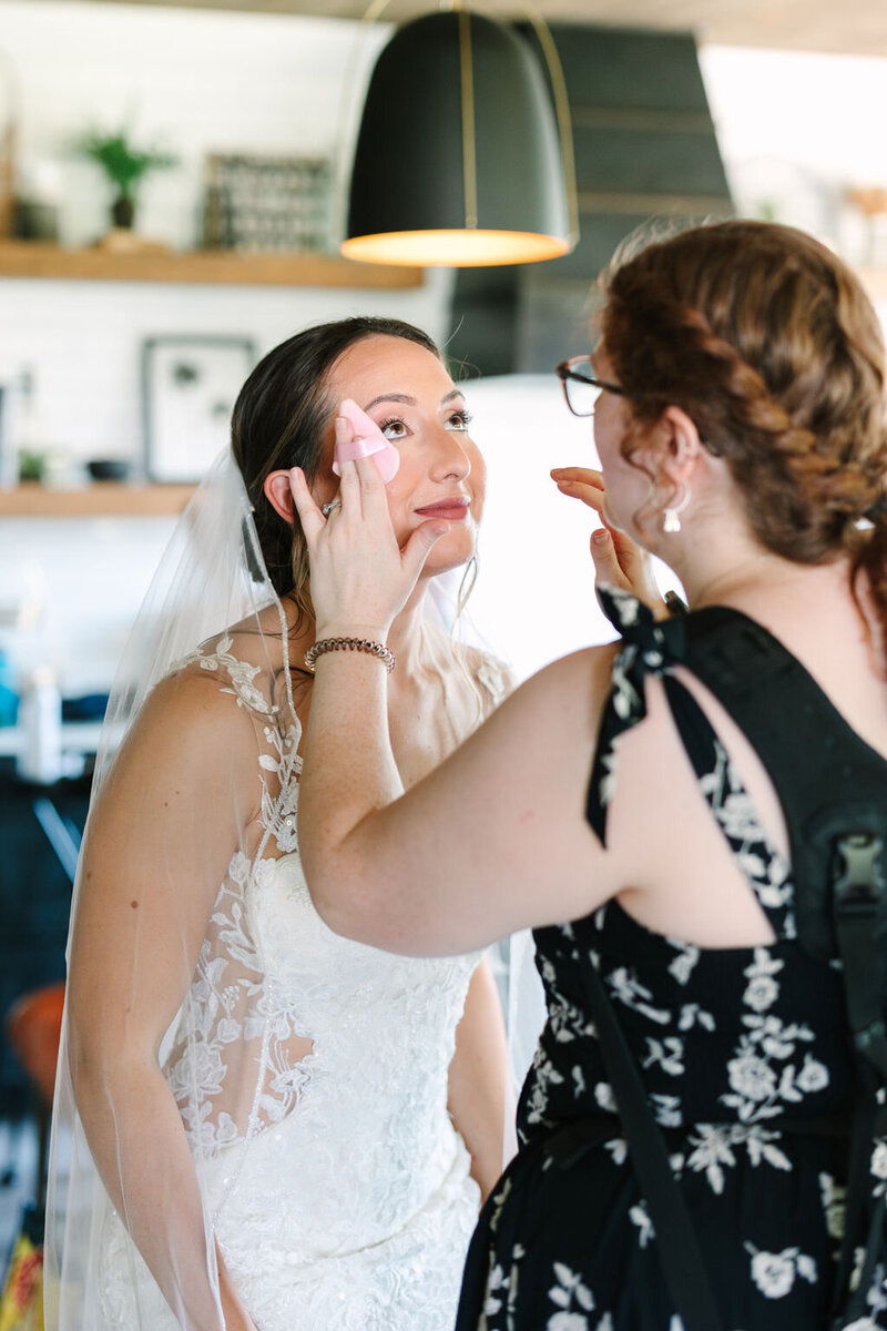 Allison Bolin Texas wedding photographer helping a bride adjust her makeup 