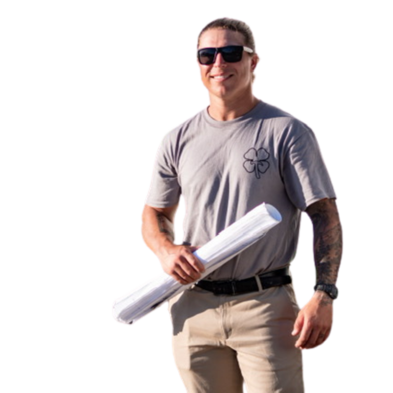 A caucasian man wearing sunglasses and a grey shirt holding plans. He is the Owner of a construction company called Shamrock Solutions Construction Inc based out of Southern California.