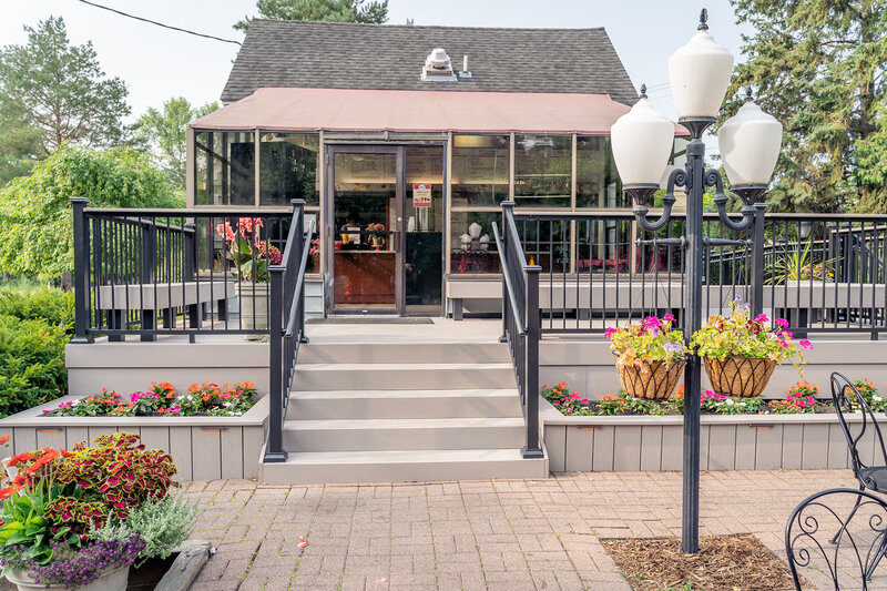 Front ground-level view of local frozen yogurt parlor with composite deck and integrated flower beds during the summer. 