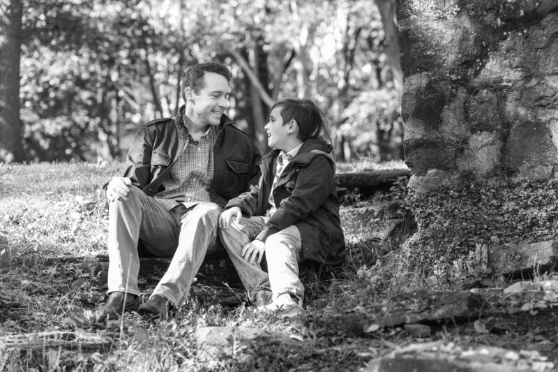 A parent sitting with their kid under a tree