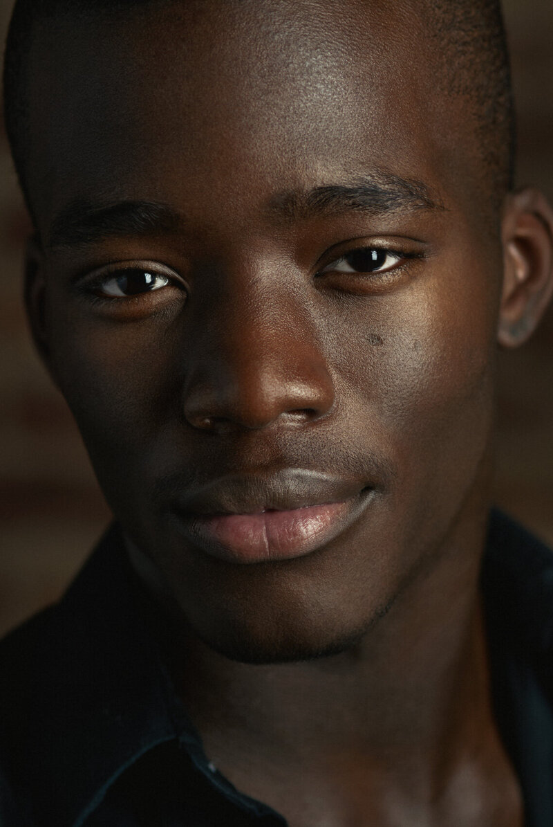 Close-up portrait of a man with a soft smile, wearing a dark suit, captured by Ylva Erevall.